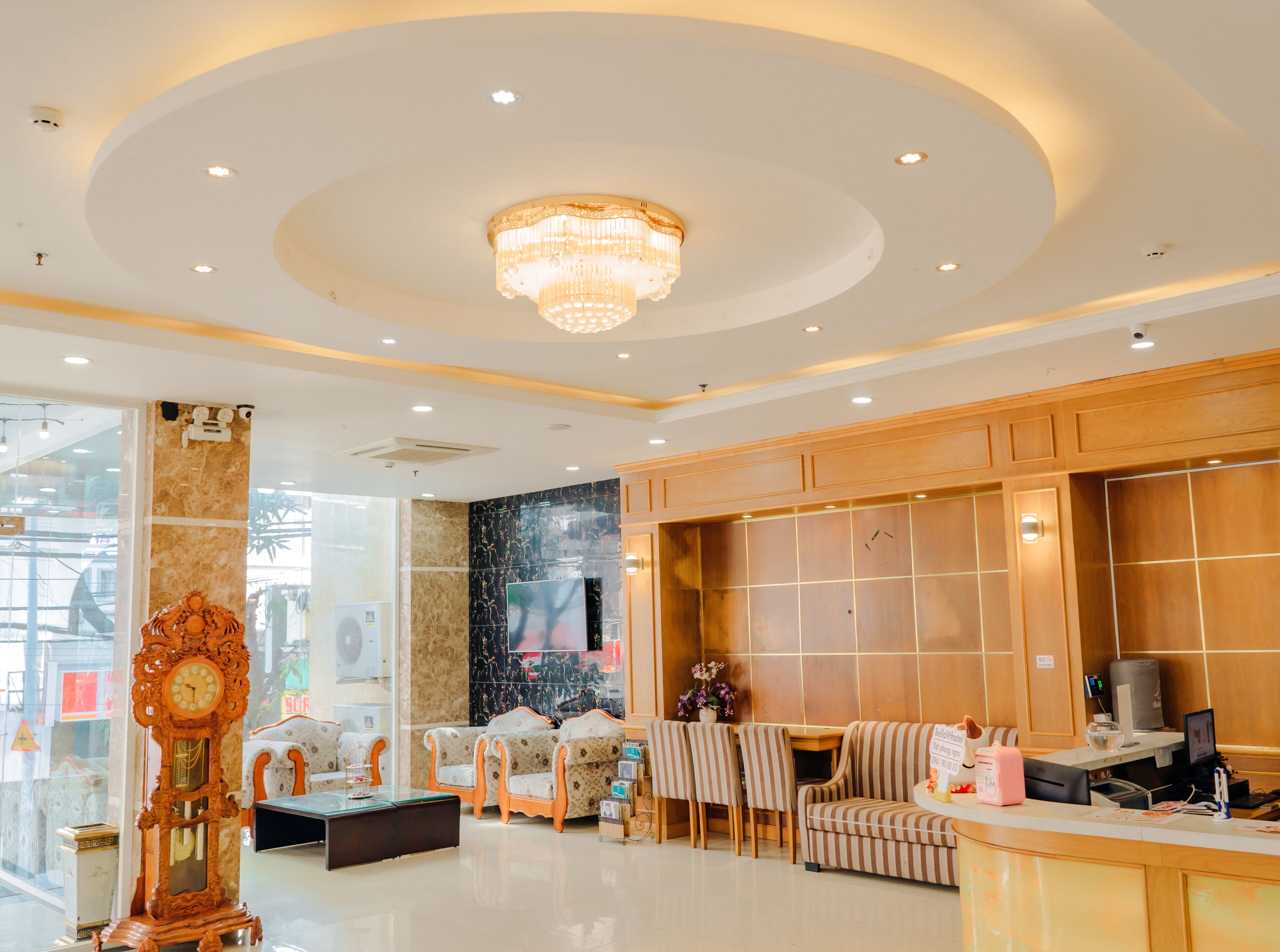 A spacious lobby with a chandelier, seating area, and a reception desk.