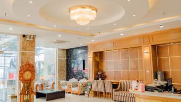 A spacious lobby with a chandelier, seating area, and a reception desk.