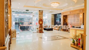 A hotel lobby with a reception desk, seating area, and a large clock. - Bella VT Hotel - Bai Sau Vung Tau (Ho Chi Minh City)