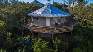 A house with a metal roof, a wooden deck, and surrounded by dense vegetation. - Indian Pass Fun,  Private & Cozy Beach Cottage--The Barnacle (Port St Joe)
