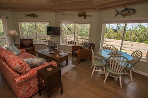 A living room with a sofa, coffee table, TV, and a dining area with chairs and a table.