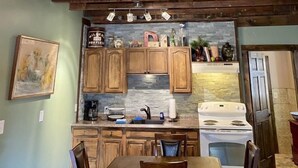 A rustic kitchen with wooden beams, a stone backsplash, and a white stove. - 1 bedroom with SPA bathroom and mountainside deck  (Jim Thorpe)