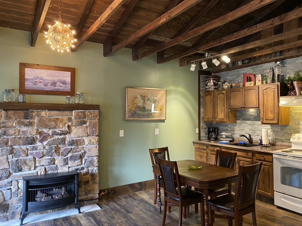 A rustic kitchen with stone walls, wooden beams, and a fireplace.