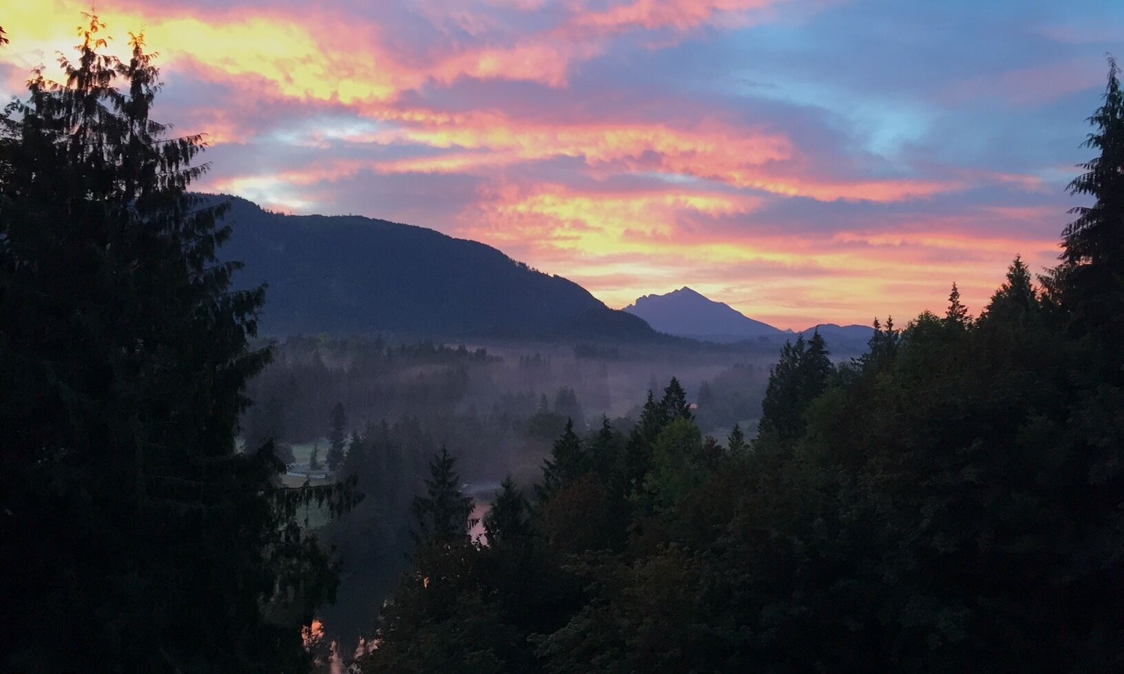 Un paysage montagneux, avec une forêt dense et un ciel dégagé.