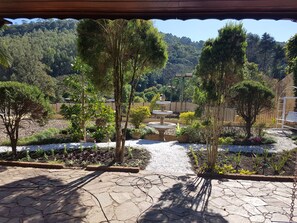 Un jardín con un sendero de piedra, una fuente y diversas plantas.