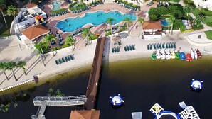Vista aérea de un complejo turístico con una gran piscina, un muelle y diversos barcos.