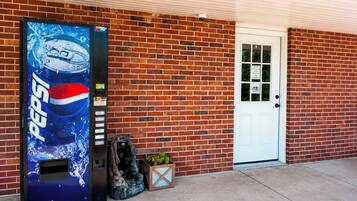 Un edificio de ladrillo con una puerta blanca y una máquina expendedora de Pepsi.
