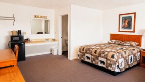 Une chambre à coucher avec un lit, un bureau avec un ordinateur, un lavabo et un miroir.
