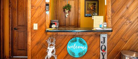 A reception desk with a 'welcome' sign, a 'joy' sign, a framed deer picture, and a 'WiFi' sign.