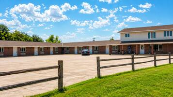 A motel with a parking lot, a car, and a grassy area.