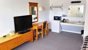 A compact hotel room with a television, wooden desk, chair, microwave, sink, and a mirror. - Drop Tyne Lodge (Franklin)