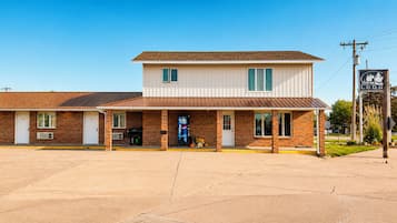 A two-story motel with a brick facade, a drive-through window, and a sign indicating a nearby lodge.