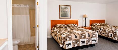 A hotel room with two beds, a bathroom, and a painting on the wall.