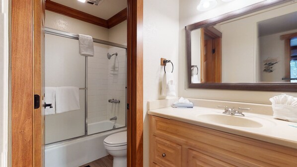A bathroom with a glass-enclosed shower, a toilet, and a vanity with a mirror. - Rustic Home, On Shuttle Route, Walk to Town, Ice Rink & Bowling, Wash/Dryer (Mammoth Lakes)