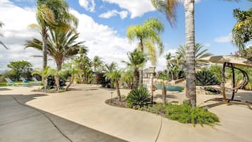 Relax in a serene outdoor oasis surrounded by lush tropical plants and comfortable lounge chairs.