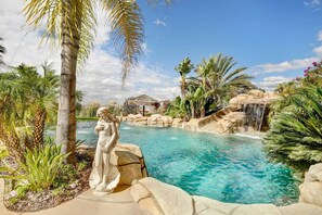 Une piscine à l’eau claire, entourée de plantes tropicales et agrémentée d’une cascade.