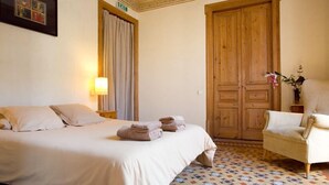 A hotel room with a bed, a chair, a wooden door, and a patterned floor. - Spectacular Apartment!, Right To The Ramblas, The Heart Of The Histori (Barcelona)