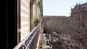 A narrow street with buildings on both sides, featuring balconies with metal railings and a palm tree. - Spectacular Apartment!, Right To The Ramblas, The Heart Of The Histori (Barcelona)