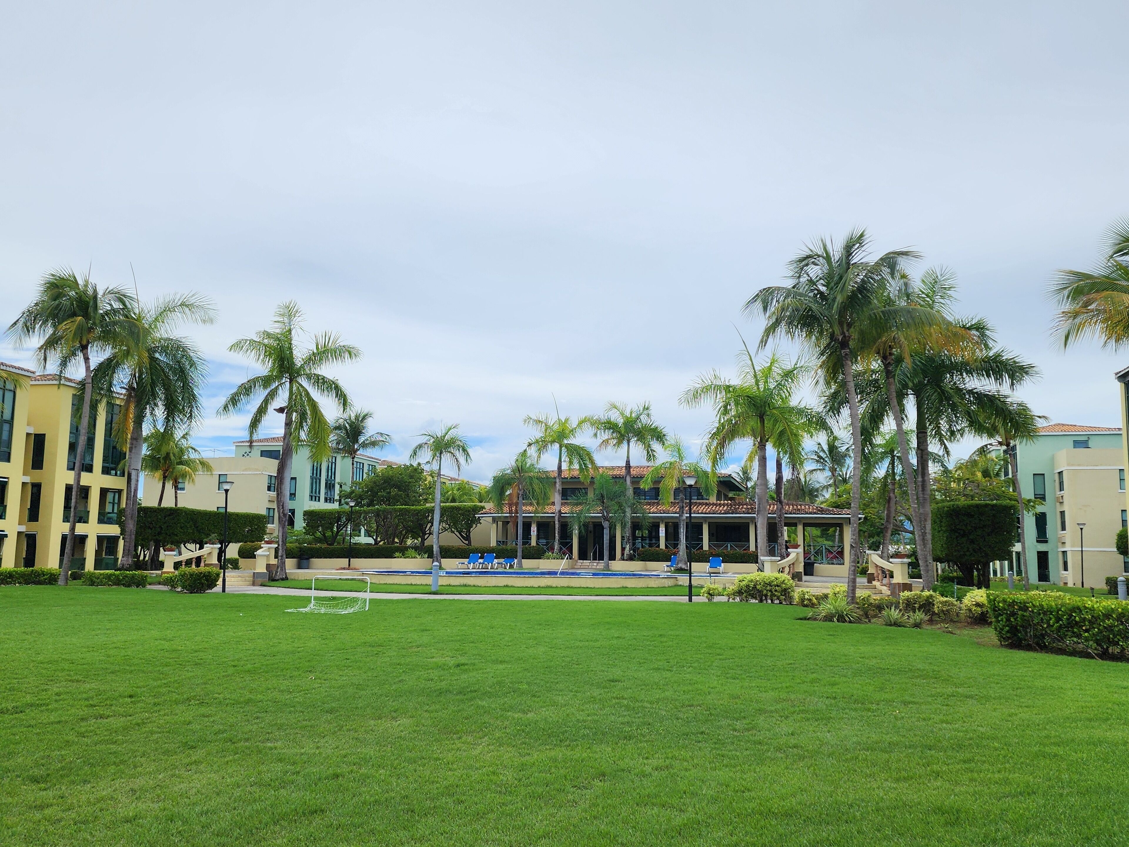 Une cour d’hôtel avec une piscine, des palmiers et une pelouse.