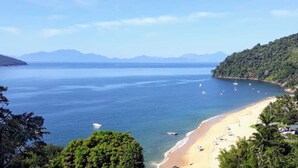 Eine Küstenlandschaft mit Strand, Booten und Bergen im Hintergrund.