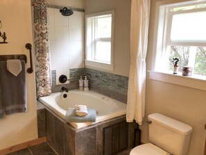 Une salle de bain avec une baignoire, des toilettes et une fenêtre.
