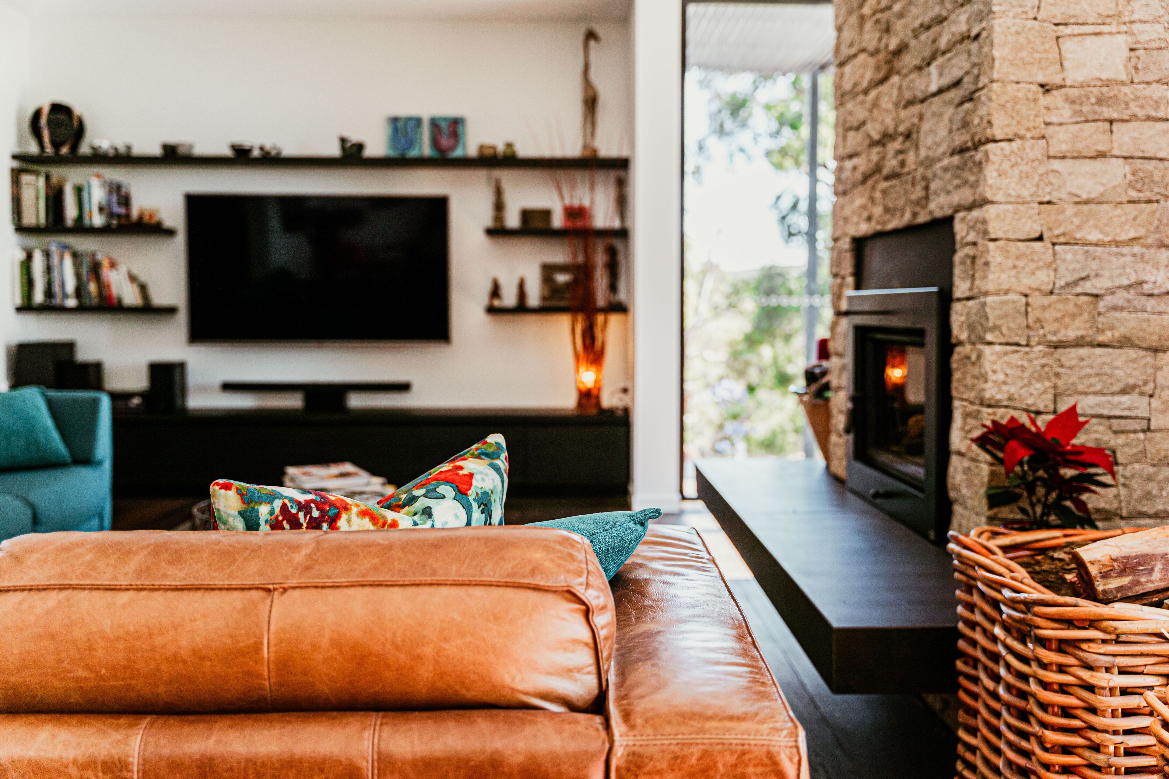 Una sala de estar moderna con un sofá de cuero, un televisor de pantalla plana, una chimenea y una estantería.