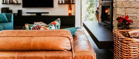 Una sala de estar moderna con un sofá de cuero, un televisor de pantalla plana, una chimenea y una estantería.