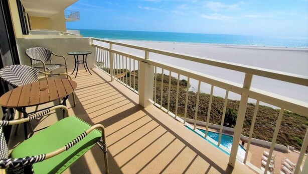 A balcony with a view of the beach and a pool. - Beachfront 1BR condo with heated pool, kitchen, WiFi, and king bed. (Marco Island)