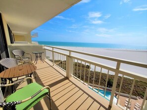 A balcony with a view of the beach and a pool. - Beachfront 1BR condo with heated pool, kitchen, WiFi, and king bed. (Marco Island)