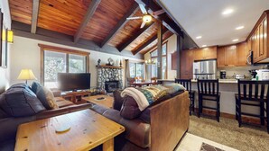 Ein gemütliches Wohnzimmer mit Kamin, Fernseher und Essbereich mit Holzmöbeln.