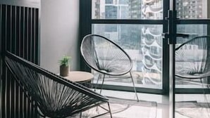Een modern balkon met twee kuipstoelen, een tafeltje en een bloempot.