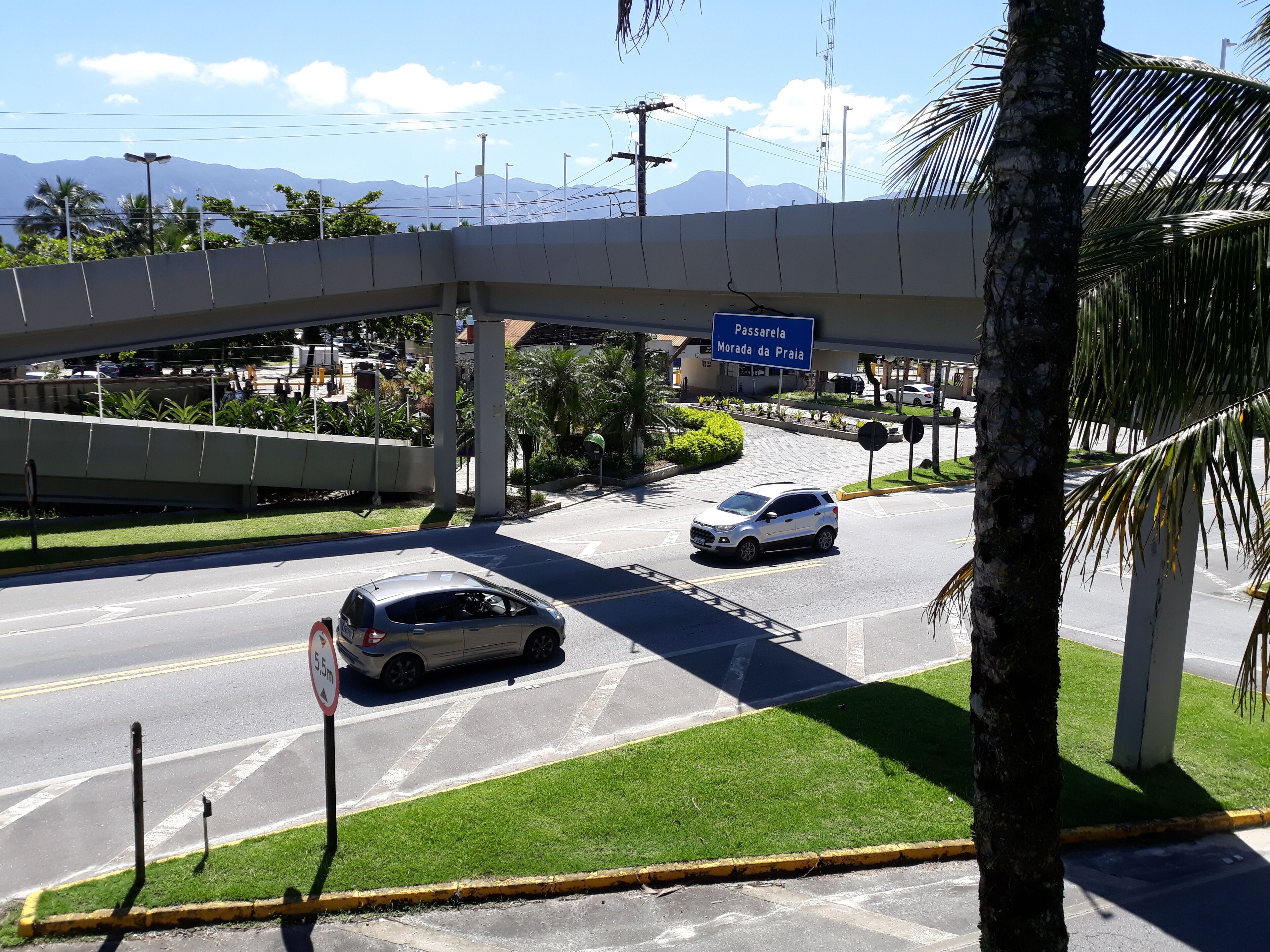 A road with vehicles, a pedestrian crossing, and a sign for Passarela Morada da Praia.