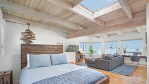 Un dormitorio espacioso con una cama grande, techo de madera y vista al océano.