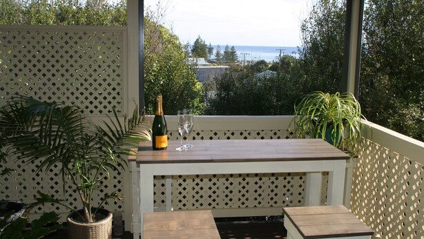 A covered patio with a wooden table and benches, a bottle of champagne, and a glass. - Spoil yourself! Gateway- McLaren Vale wineries, Moana Beach & Onkaparinga Gorge! (Moana)