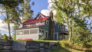 Une jetée en bois s’étendant au-dessus d’une étendue d’eau, menant à une maison avec un toit rouge et des murs en pierre.