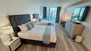 Habitación de hotel con dos camas, un escritorio, un televisor y vistas a la ciudad.