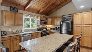 A kitchen with wooden cabinets, granite countertops, stainless steel appliances, and a large island. - Moonridge Memories - 5 Bedroom, Hot Tub, Game Room, Pool Table (Big Bear City)