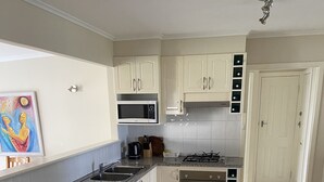 A kitchen with white cabinets, a granite countertop, a microwave, a gas stove, and a sink.