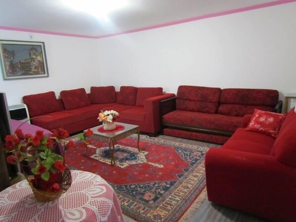 A living room with red sofas, a coffee table, and a patterned rug. - Comfortable house, 6 bedrooms with air conditioning and Wi-Fi. (Olímpia)