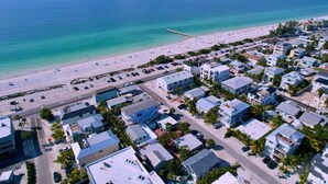 A coastal residential area with beachfront properties, a pier, and a beach with people and vehicles.