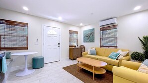 A modern living room with a yellow sofa, a round coffee table, and a white door.