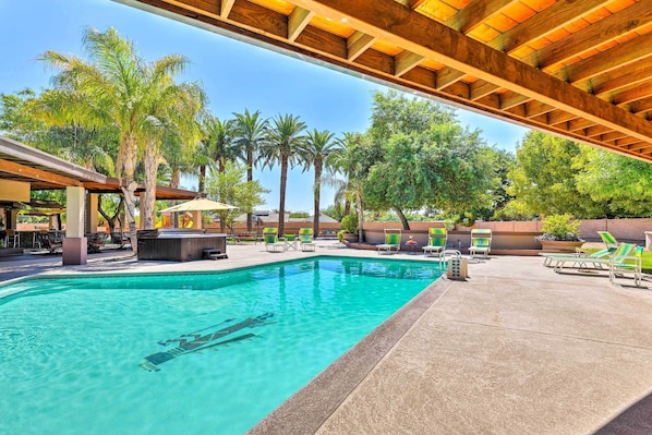 A pool area with clear water, lounge chairs, and palm trees.