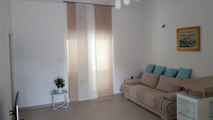 A modern living room with a beige sofa, a small side table with a plant, and a painting on the wall. - suite for relaxing croatia (Korčula)