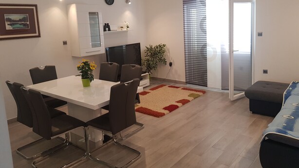 A modern living room with a dining area, a sofa, a TV, and a sliding glass door leading to a balcony. - suite for relaxing croatia (Korčula)
