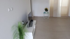 A modern living room with a flat-screen TV, a small table with a plant, and a sliding door leading to another room. - suite for relaxing croatia (Korčula)