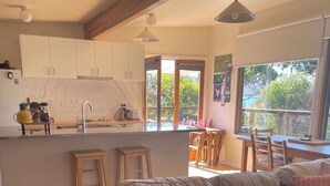 Una cocina moderna con armarios blancos, una isla central y un comedor con muebles de madera.