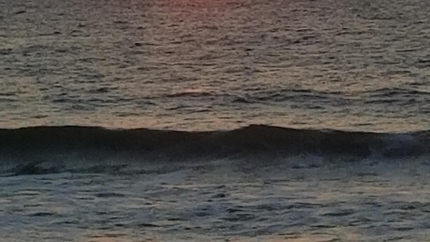 Un atardecer sobre el océano con olas tranquilas.
