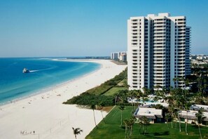 A beachfront hotel with multiple high-rise buildings, a sandy beach, and a clear blue ocean. - Beachfront 2BR/2BA condo in Marco Island with heated pool, WiFi, and balcony views. (Marco Island)