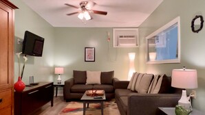 Un salon équipé d’un ventilateur de plafond, d’une télévision, d’un canapé, d’une table basse et d’une petite table avec une lampe.