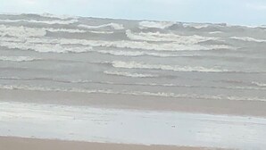 Une plage où les vagues se brisent sur le rivage sous un ciel nuageux.
